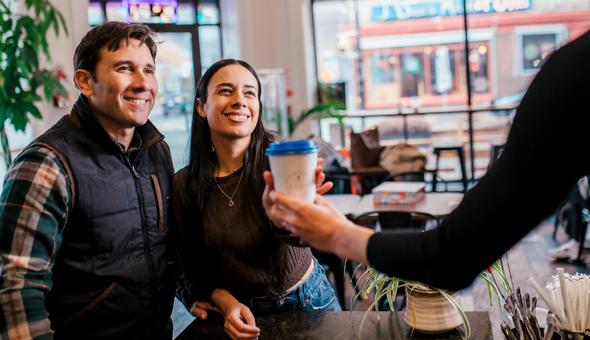 two people smiling at a person with a drink