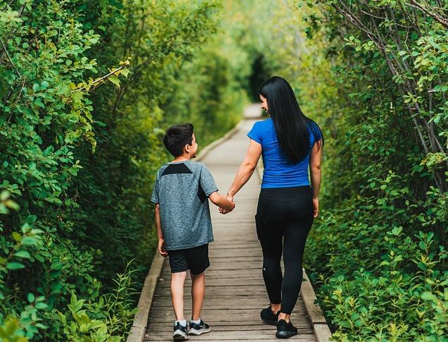A mother and her son walking on a path into a forest