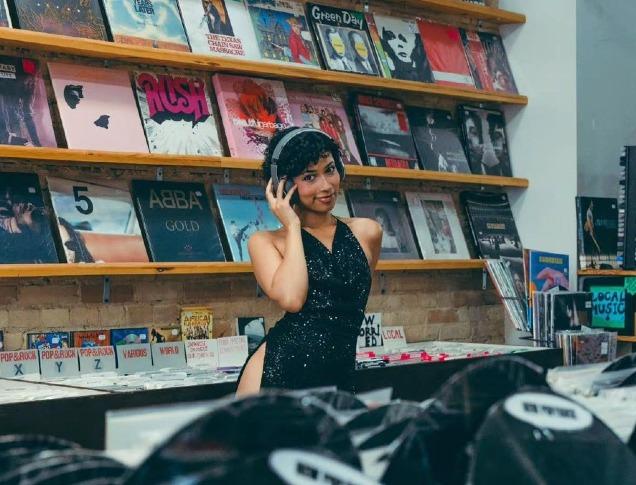 A woman wearing headphones stands in a record shop in London, Ontario.