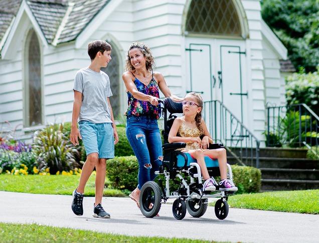 A family with a child in a wheelchair going for a walk on a paved walkway in Storybook Gardens located in London, Ontario