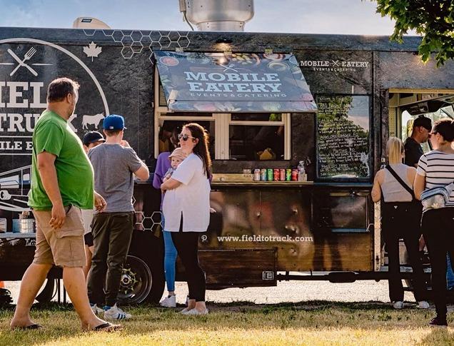 People standing in front of a food truck waiting to order from Field to Truck in London, Ontario