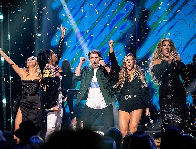 co-hosts and music artists celebrate on stage with confetti in the air
