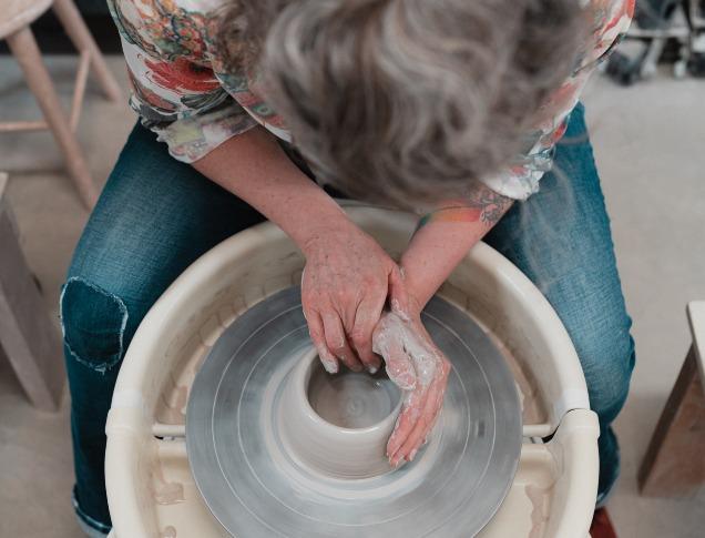 View from above as a woman turns a pottery bowl on a wheel.