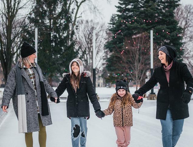 4 people holding hands and skating on the skating rink in Victoria Park locate din London, Ontario