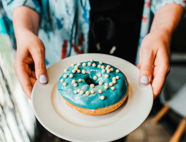 Woman holding a vanilla donut from Happiness Cafe located in London, Ontario