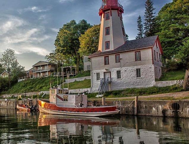 A small boat at a dock in front of a lighthouse in Goderich.