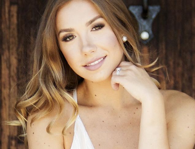 Female country Musician Genevieve Fisher standing in front of fence