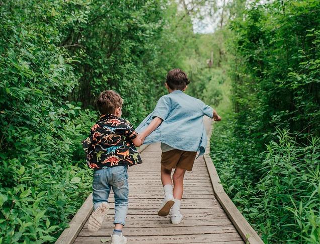 Two young boys holding hands and running down a path in Westminster Ponds located in London, Ontario