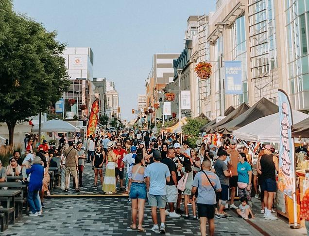 A colourful and busy street of people during an outdoor festival in London, Ontario.