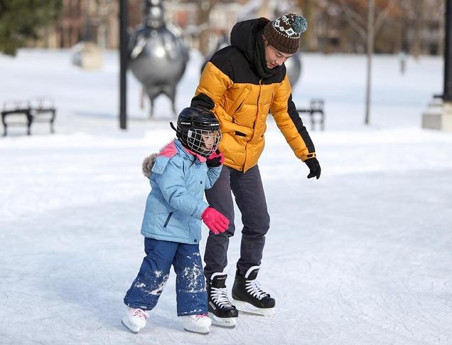 A father and daughter skating outdoors at Springbank Park in London, Ontario