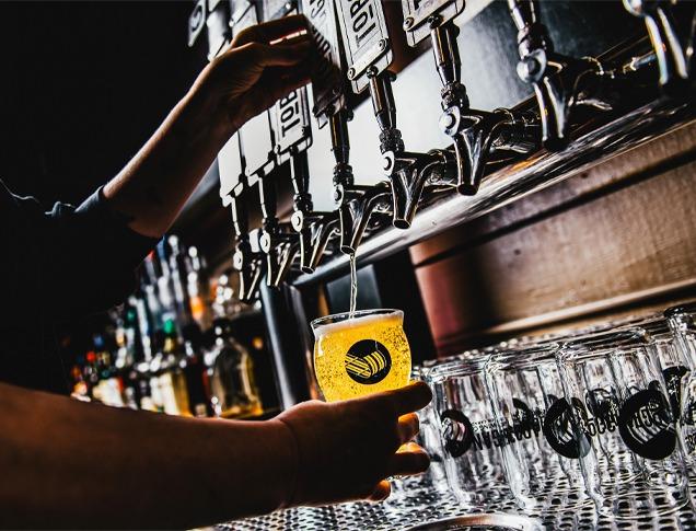 A bartender filling up a glass of draft beer in a bar located in London, Ontario