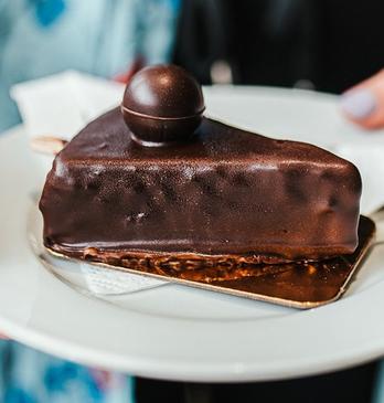 A female holding a slice of chocolate cake on a plate