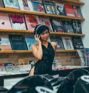 A woman wearing headphones stands in a record shop in London, Ontario.