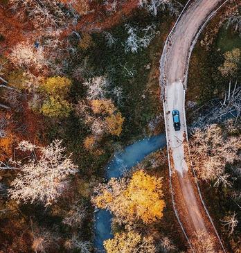 Aerial view of a car driving down a curving road with fall colours in London, Ontario, Canada.