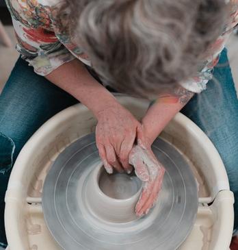View from above as a woman turns a pottery bowl on a wheel.