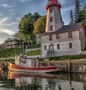 A small boat at a dock in front of a lighthouse in Goderich.