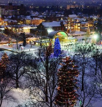 Aerial view of Victoria Park with lit up trees and people skating on the ice rink during the holiday season located in London, ON