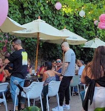 Groups of people sitting and standing outdoors on a summer day at Che Restobar's patio located in London, Ontario