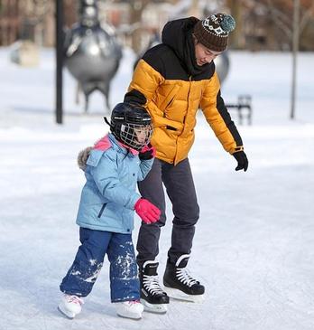 A father and daughter skating outdoors at Springbank Park in London, Ontario