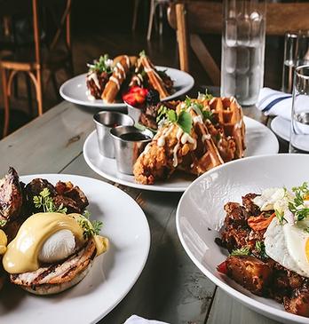 three plates of brunch inspired food on a grey wooden table