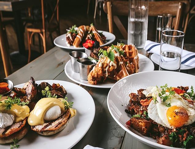 three plates of brunch inspired food on a grey wooden table