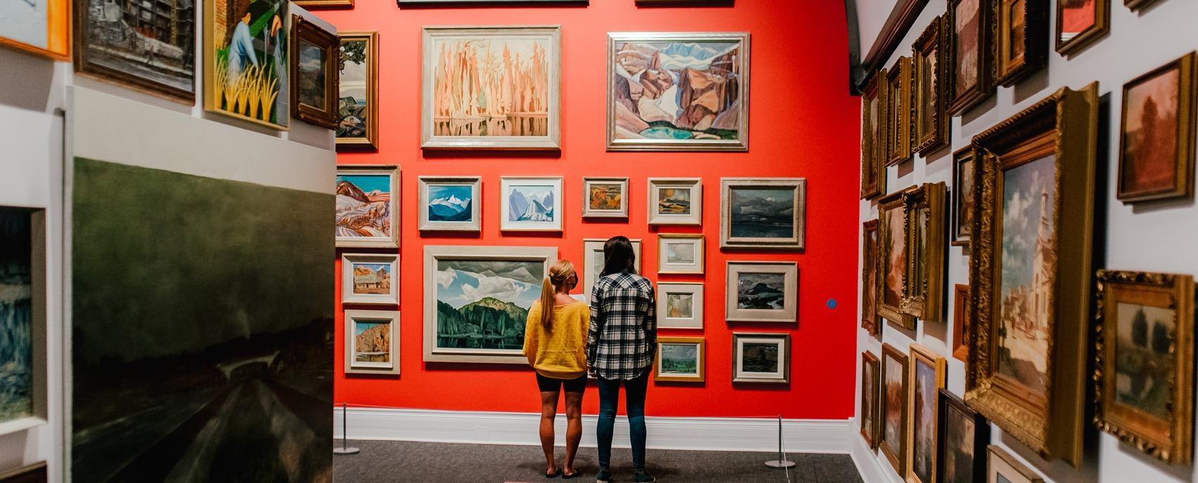 Two females looking at various paintings on display from the Group of Seven in Museum London located in London, Ontario