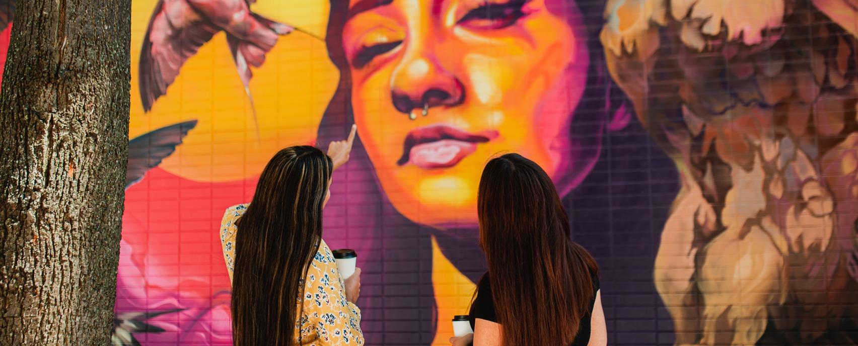 Two females looking at a mural located at Market Lane in downtown London, Ontario