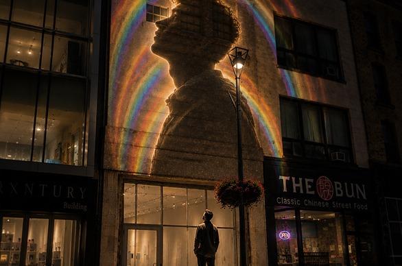 A person looking at projected artwork on a building at night