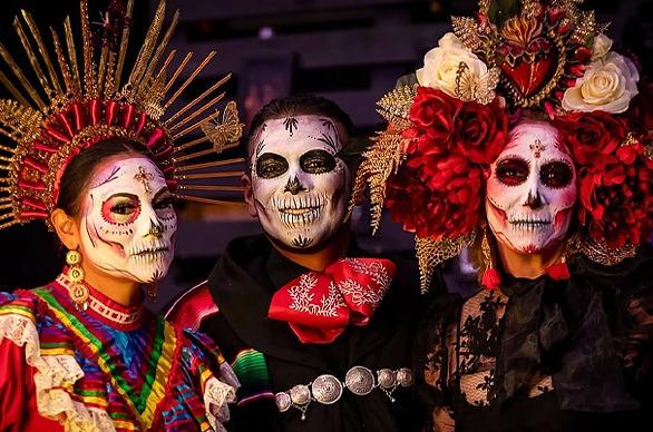 Three people dressed in Day of the Dead (Día de Muertos) costumes with skeleton themed makeup