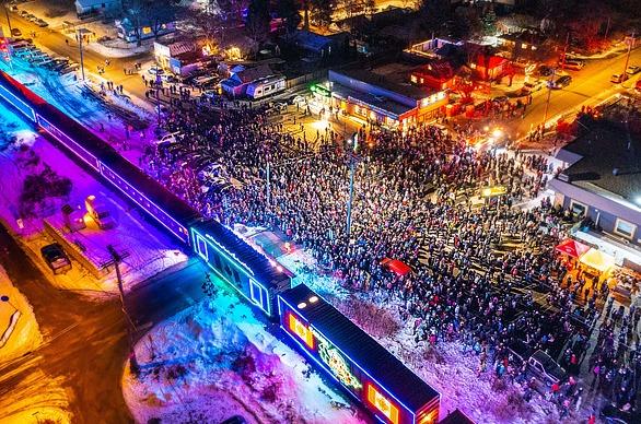A large crowd gathered outdoors in the winter to view the CPKC Holiday Train