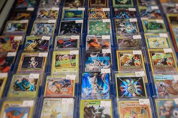A grouping of rare Pokemon cards on display, covered in a plastic casing with price stickers on them