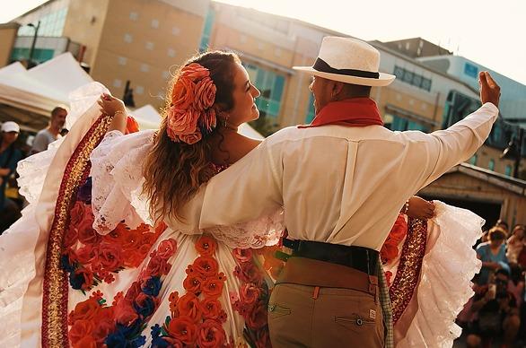 A couple is dancing in traditional Columbian clothing outdoors at the Colombian Gastronomy Festival in London, Ontario