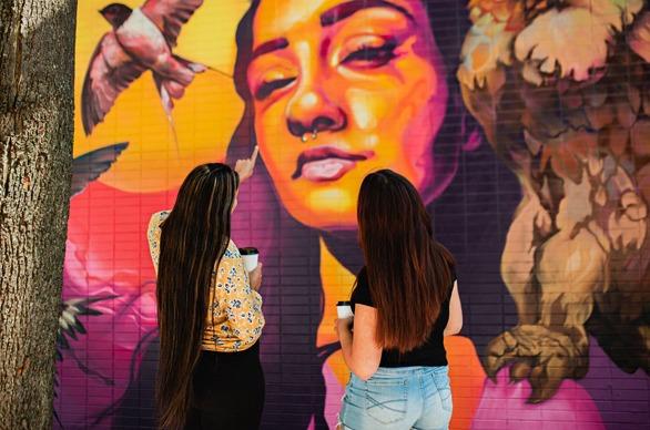 Two females observing a large painted mural in downtown London, Ontario