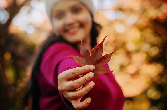 A female holding a maple leaf outdoors during the season of Fall in London, Ontario