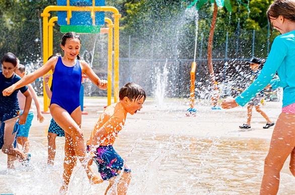 A group of young children splashing water and having fun at East Park's splash pad located in London, Ontario