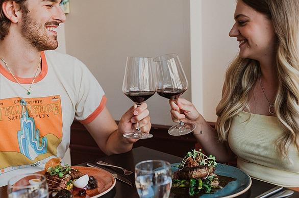 A couple holding their glasses of wine and enjoying a meal at Garlic's Restaurant located in London, Ontario