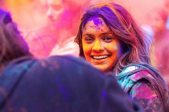 A group of people celebrating with bright coloured powder on their faces and surrounding them