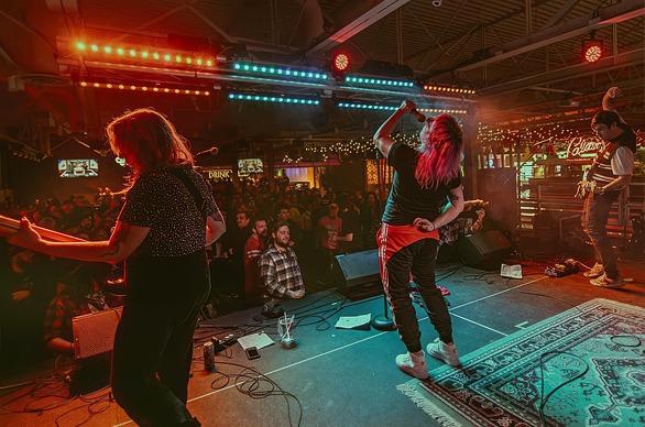 Musicians in a band playing live on stage to a large crowd at Palasad Social Bowl located in London, Ontario