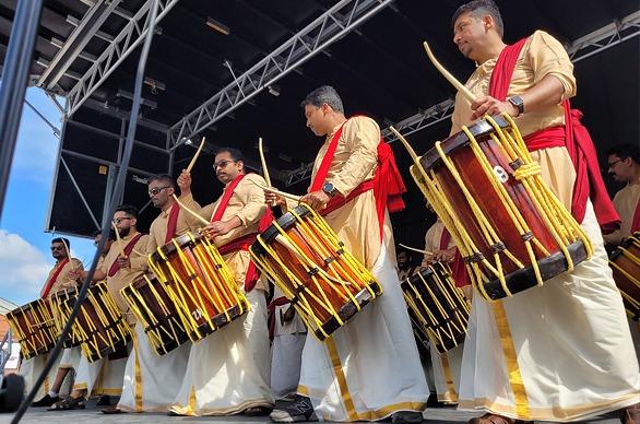 A group of musicians hitting a drum harnessed onto their bodies for an event at Covent Garden Market in London, Ontario
