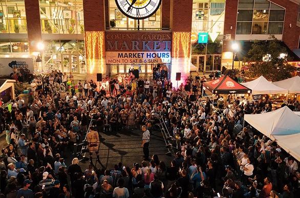 A large gathered outdoors at night in front of Covent Garden Market, located in London, Ontario