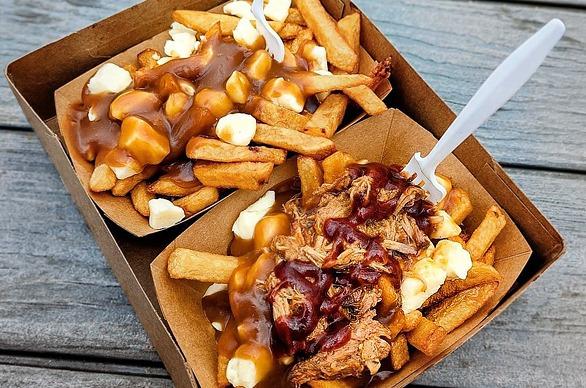 A table top view of a serving of poutine on a wooden table