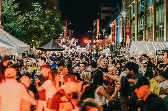 A large group of people gathered outdoors on Dundas Street in downtown London, Ontario during a festival at night