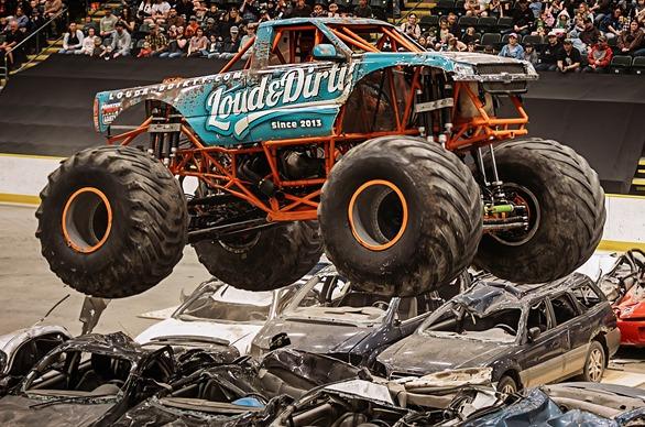 The monster truck, Loud & Dirty jumping over a group of crushed cars with a large crowd watching in the background