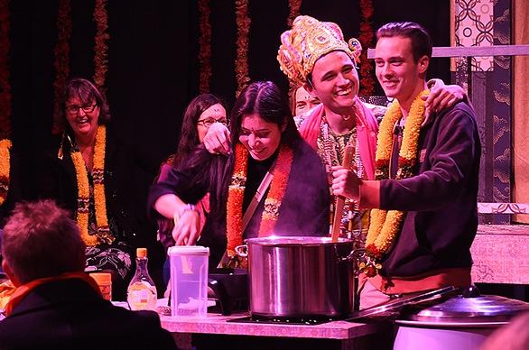 Various people on stage and audience members watching Mrs. Krishnan’s Party, an immersive theatrical experience