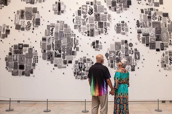 A couple holding hands and looking at a wall with various pieces of artwork on it at Museum London