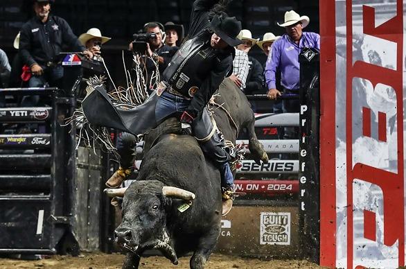 A bull rider performing at the Professional Bull Riders Classic show with an aggressive bull