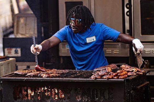 A male adding BBQ sauce on ribs cooking on a coal fired grill from Ribfest located in London, Ontario