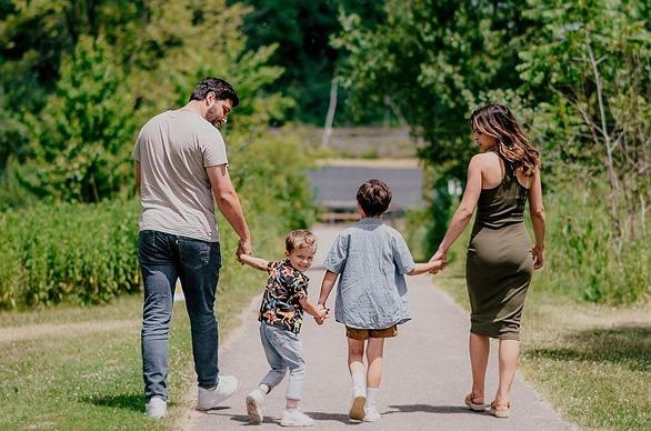 A family walking down a paved path surrounded by large trees in Westminster Ponds located in London, Ontario