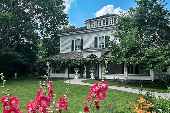 Front view of the Eldon House building surrounded by trees and flowers on a bright summer day in London, Ontario
