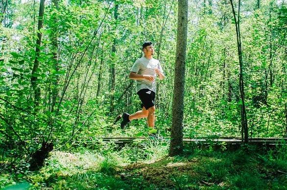 A male running on a path outdoors surrounded by trees in London, Ontario